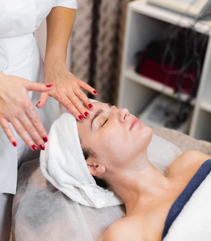 Esthéticienne réalisant un massage du visage relaxant pendant un soin en institut de beauté