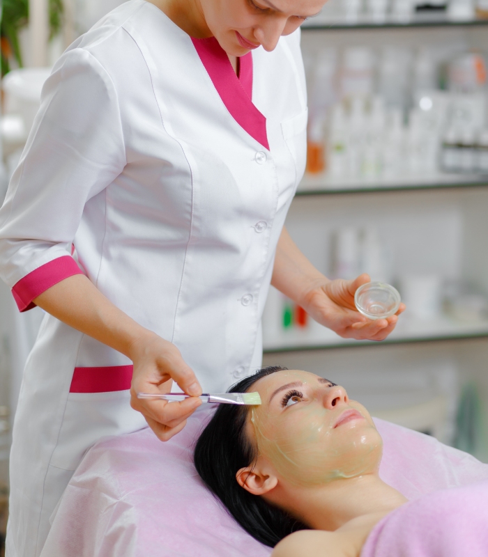 Esthéticienne appliquant un masque visage au pinceau lors d-un soin en institut de beauté