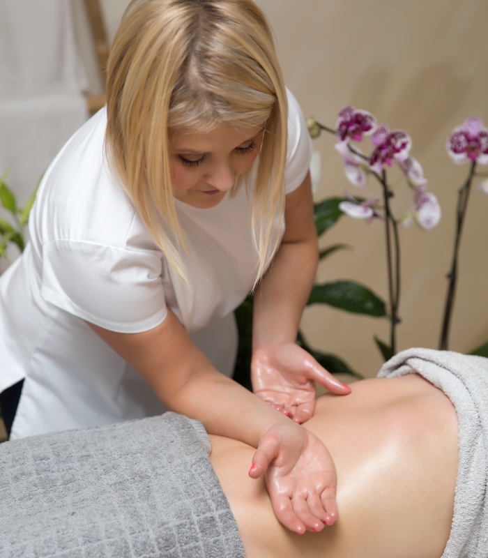 Esthéticienne réalisant un massage du dos lors d-un soin du corps en institut de beauté