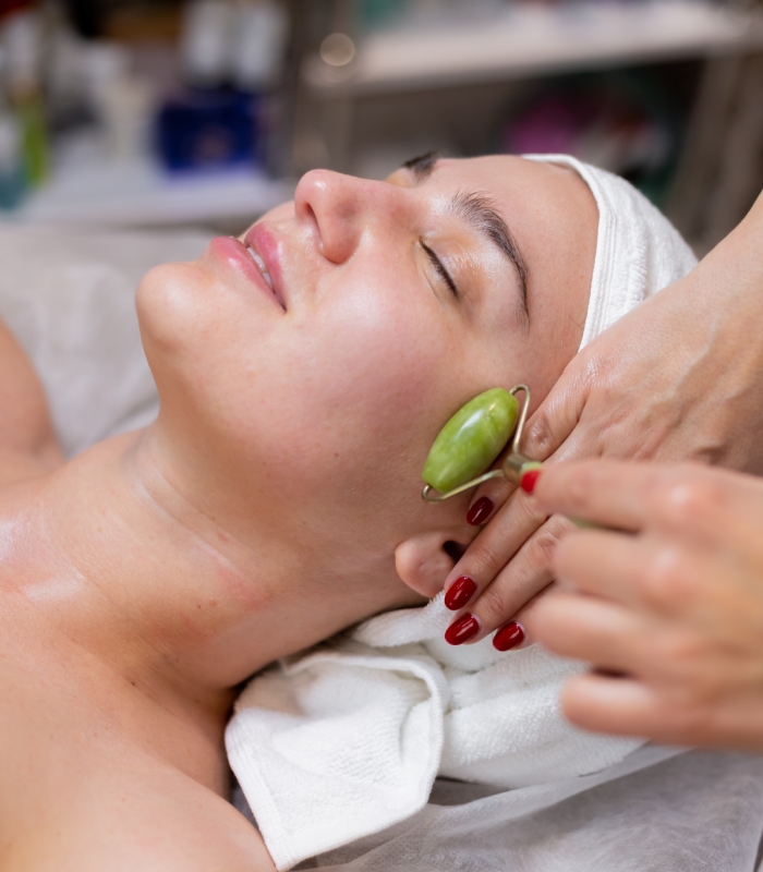 Soin du visage avec rouleau en pierre naturelle en institut de beauté